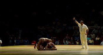 Movie still from “Foxcatcher” (2014), directed by Bennett Miller – Two men are wrestling in a wrestling match; Wide shot, Low angle