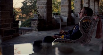 Movie still from “Foxcatcher” (2014), directed by Bennett Miller – A man sitting on a chair with a cell phone in his hand; Medium shot, Over the shoulder angle