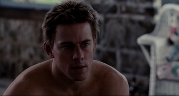 Movie still from “Foxcatcher” (2014), directed by Bennett Miller – A shirtless man with spiky hair looking at the camera; Close Up shot, Over the shoulder angle