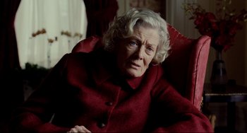 Movie still from “Foxcatcher” (2014), directed by Bennett Miller – An older woman sitting in a red chair; Close Up shot, Over the shoulder angle
