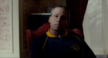 Movie still from “Foxcatcher” (2014), directed by Bennett Miller – A man sitting in a red chair with his mouth open; Close Up shot, Over the shoulder angle