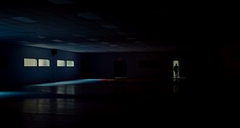 Movie still from “Foxcatcher” (2014), directed by Bennett Miller – A person standing in a dark room with a light on; Extreme Wide shot, Low angle