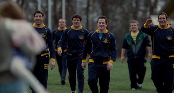 Movie still from “Foxcatcher” (2014), directed by Bennett Miller – A group of young men walking across a grass field; Medium shot, Over the shoulder angle