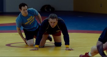 Movie still from “Foxcatcher” (2014), directed by Bennett Miller – A man and a woman are wrestling on a mat; Medium shot, High angle