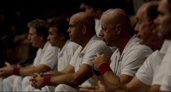 Movie still from “Foxcatcher” (2014), directed by Bennett Miller – A group of men sitting next to each other in white shirts; Medium shot, High angle