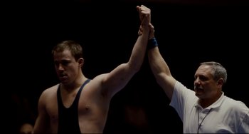 Movie still from “Foxcatcher” (2014), directed by Bennett Miller – Two men holding hands while one of them is holding the other hand up; Medium shot, Low angle