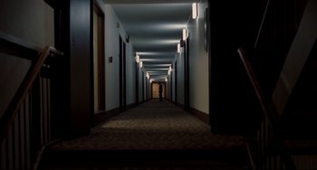Movie still from “Foxcatcher” (2014), directed by Bennett Miller – A person is walking down a hallway in a building; Extreme Wide shot, High angle
