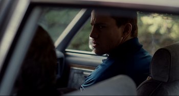 Movie still from “Foxcatcher” (2014), directed by Bennett Miller – A man sitting in the passenger seat of a car; Close Up shot, Over the shoulder angle