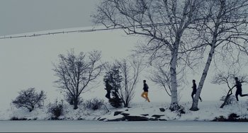 Movie still from “Foxcatcher” (2014), directed by Bennett Miller – A person running in the snow near a tree; Extreme Wide shot, Low angle