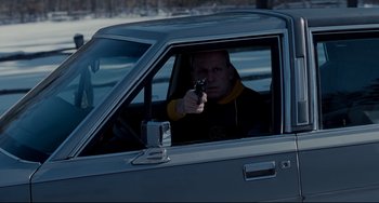 Movie still from “Foxcatcher” (2014), directed by Bennett Miller – A man holding a gun in the driver's seat of a car; Medium shot, High angle