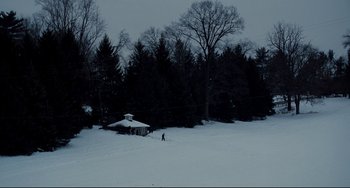 Movie still from “Foxcatcher” (2014), directed by Bennett Miller – A person is standing in the middle of a snow covered field; Extreme Wide shot, High angle