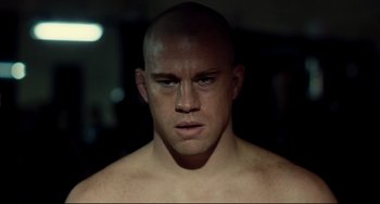 Movie still from “Foxcatcher” (2014), directed by Bennett Miller – A person with a shaved head; Close Up shot, Over the shoulder angle