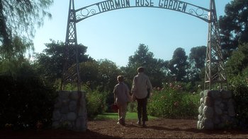 Movie still from “Frailty” (2001), directed by Bill Paxton – Two people are walking under a sign that says thurman rose garden; Wide shot, Low angle