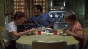 Movie still from “Frailty” (2001), directed by Bill Paxton – A group of people sitting at a table eating; Medium shot, Low angle