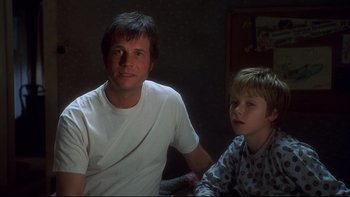 Movie still from “Frailty” (2001), directed by Bill Paxton – A man and a boy sitting next to each other in a dark room; Close Up shot, Over the shoulder angle