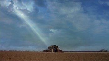 Movie still from “Frailty” (2001), directed by Bill Paxton – An old barn in the middle of a field under a cloudy sky; Extreme Wide shot, Low angle