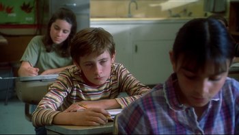 Movie still from “Frailty” (2001), directed by Bill Paxton – A boy is writing on a piece of paper while two other girls look on; Close Up shot, Low angle