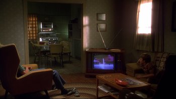Movie still from “Frailty” (2001), directed by Bill Paxton – A man sitting in front of an old television; Wide shot, High angle