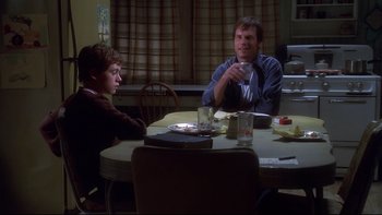Movie still from “Frailty” (2001), directed by Bill Paxton – Two people sitting at a table in front of each other; Medium shot, Over the shoulder angle