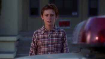 Movie still from “Frailty” (2001), directed by Bill Paxton – A young man standing in front of a car on the street; Close Up shot, Over the shoulder angle