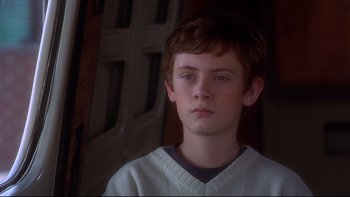 Movie still from “Frailty” (2001), directed by Bill Paxton – A young boy in a baseball uniform looking into the distance; Close Up shot, Over the shoulder angle