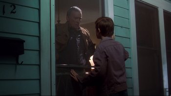 Movie still from “Frailty” (2001), directed by Bill Paxton – An older man and a young boy looking at each other through a window; Medium shot, Over the shoulder angle