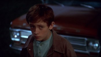 Movie still from “Frailty” (2001), directed by Bill Paxton – A young boy in a brown jacket looking to his left; Close Up shot, High angle