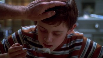 Movie still from “Frailty” (2001), directed by Bill Paxton – A person holding a spoon in their hand while a boy is eating something; Close Up shot, Over the shoulder angle