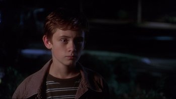 Movie still from “Frailty” (2001), directed by Bill Paxton – A young boy in a striped shirt and brown jacket; Close Up shot, High angle