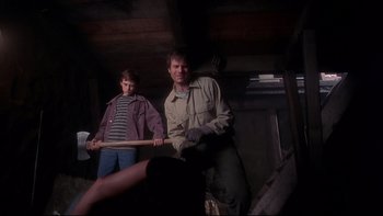 Movie still from “Frailty” (2001), directed by Bill Paxton – A man holding a baseball bat while another man watches; Medium shot, Low angle