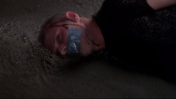 Movie still from “Frailty” (2001), directed by Bill Paxton – A man with tape over his mouth laying on the ground; Close Up shot, Overhead angle