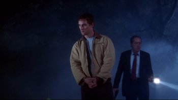 Movie still from “Frailty” (2001), directed by Bill Paxton – A man standing in front of another man in a suit and tie; Medium shot, Low angle