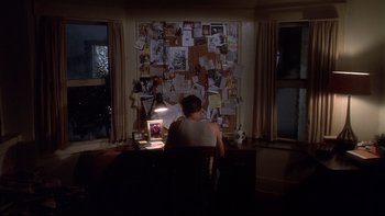 Movie still from “Frailty” (2001), directed by Bill Paxton – A person sitting at a desk with a laptop; Wide shot, High angle