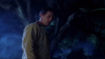 Movie still from “Frailty” (2001), directed by Bill Paxton – A man standing next to a tree at night; Medium shot, Low angle