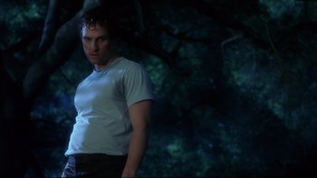 Movie still from “Frailty” (2001), directed by Bill Paxton – A man standing in front of a tree in the dark; Medium shot, Low angle