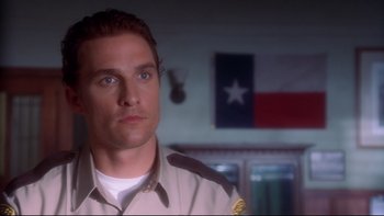 Movie still from “Frailty” (2001), directed by Bill Paxton – A man in a uniform is standing in front of a texas flag; Close Up shot, Low angle
