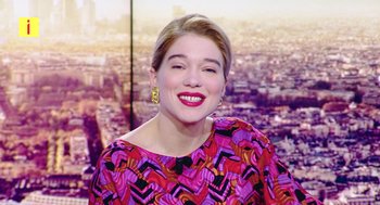 Movie still from “France” (2021), directed by Bruno Dumont – A woman in a colorful dress smiling for the camera; Medium shot, Low angle