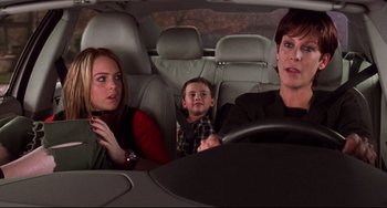 Movie still from “Freaky Friday” (2003), directed by Mark Waters – Two people and a small child in the back seat of a car; Medium shot, Over the shoulder angle