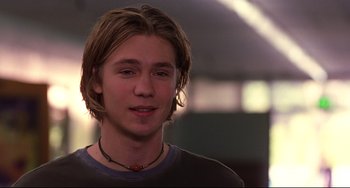 Movie still from “Freaky Friday” (2003), directed by Mark Waters – A man with long blonde hair wearing a black shirt; Close Up shot, Low angle
