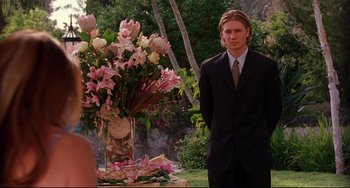 Movie still from “Freaky Friday” (2003), directed by Mark Waters – A man standing in front of a table with flowers; Medium shot, Over the shoulder angle