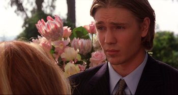 Movie still from “Freaky Friday” (2003), directed by Mark Waters – A man in a suit and tie standing next to flowers; Close Up shot, Over the shoulder angle