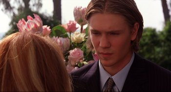 Movie still from “Freaky Friday” (2003), directed by Mark Waters – A man in a suit and tie talking to a woman in front of some flowers; Close Up shot, Over the shoulder angle
