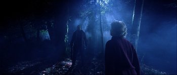 Movie still from “Freddy vs. Jason” (2003), directed by Ronny Yu – A man and a woman in the woods holding guns; Wide shot, Low angle