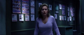 Movie still from “Freddy vs. Jason” (2003), directed by Ronny Yu – A woman standing in front of a bunch of posters on a wall; Medium shot, Over the shoulder angle