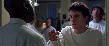 Movie still from “Freddy vs. Jason” (2003), directed by Ronny Yu – A young man holding a cigarette in front of a group of people; Close Up shot, Over the shoulder angle