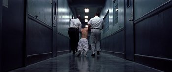 Movie still from “Freddy vs. Jason” (2003), directed by Ronny Yu – A man being held down in a hallway by two police officers; Wide shot, High angle