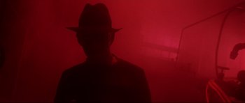 Movie still from “Freddy vs. Jason” (2003), directed by Ronny Yu – A man wearing a hat standing in front of a red wall; Close Up shot, Low angle