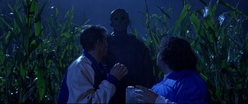 Movie still from “Freddy vs. Jason” (2003), directed by Ronny Yu – Two men and a woman looking at a statue in a corn field at night; Medium shot, Over the shoulder angle