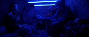 Movie still from “Freddy vs. Jason” (2003), directed by Ronny Yu – Two people sitting in a room with a blue light; Medium shot, High angle