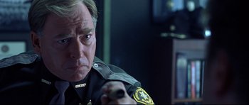 Movie still from “Freddy vs. Jason” (2003), directed by Ronny Yu – A man in a police uniform looking at the camera; Close Up shot, Over the shoulder angle